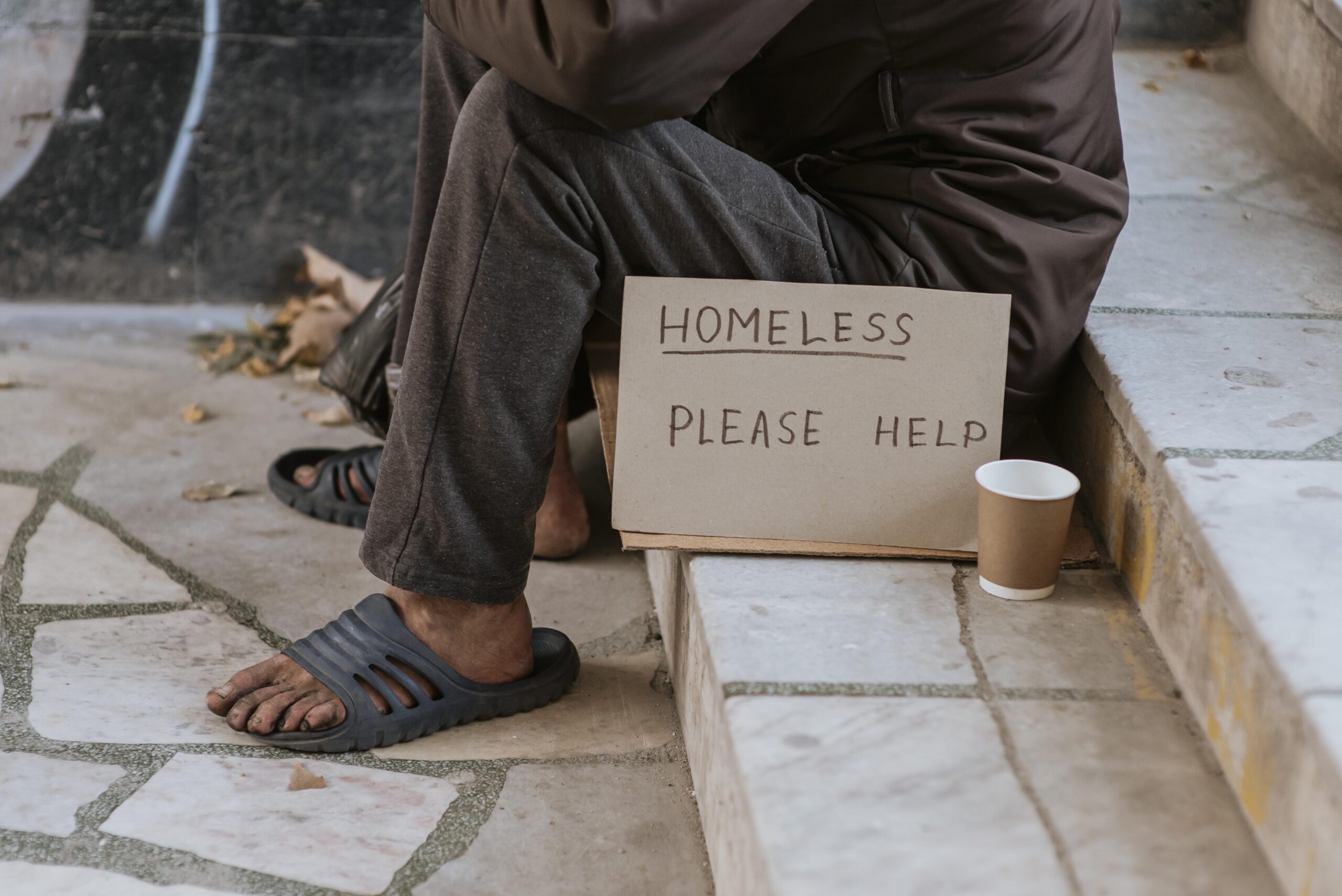 front view homeless man stairs with help sign cup scaled